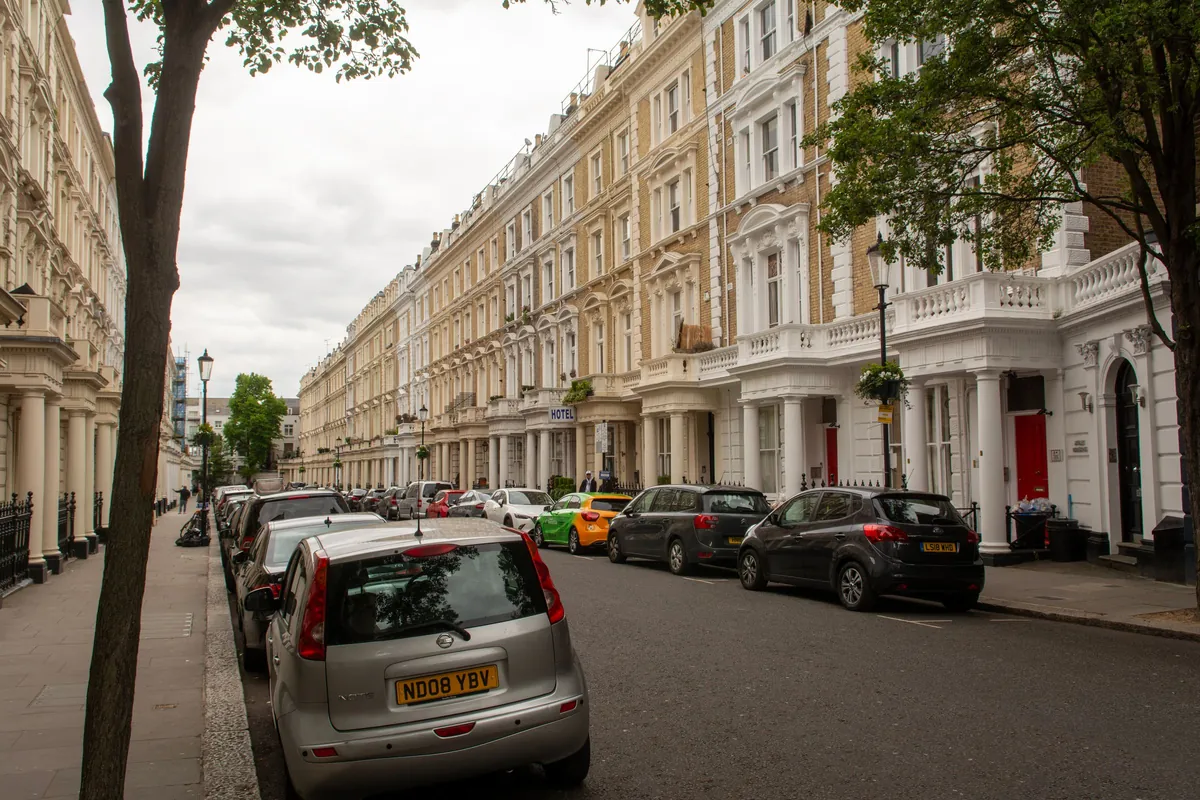 Stucco-fronted London terrace with parked cars