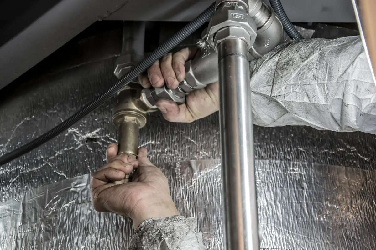 Plumber tightening a pipe joint beneath a sink